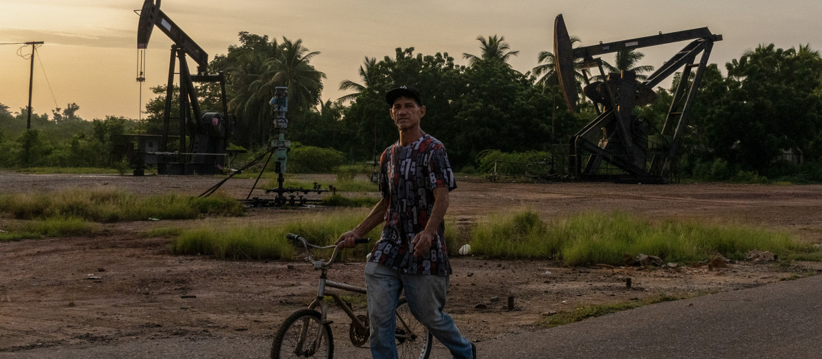 Un hombre empuja una bicicleta frente a pozos petroleros abandonados en Maracaibo, estado Zulia, Venezuela