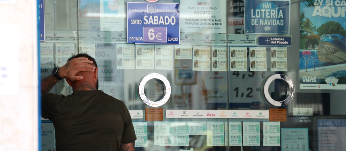 Una persona comprando un boleto en una Administración de Loterias, en el centro de Sevilla