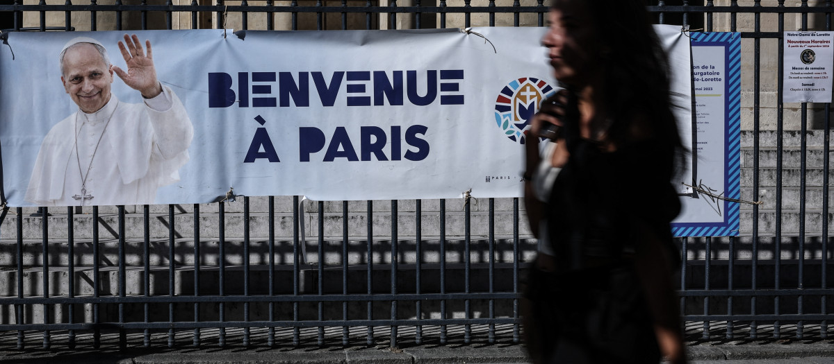 Una pancarta con la imagen del papa León XIV y el mensaje «Bienvenidos a París» adorna las rejas de la iglesia de Notre-Dame-de-Lorette mientras un peatón pasa por allí