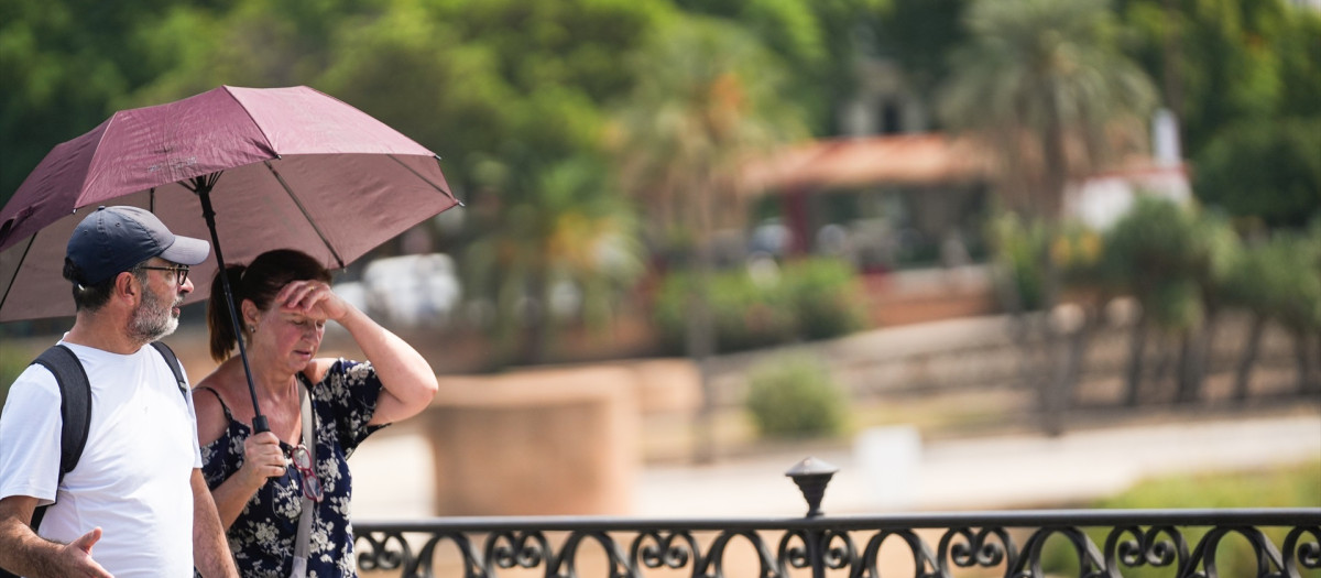 Dos personas con sombrilla y ropa veraniega durante una jornada de intenso calor