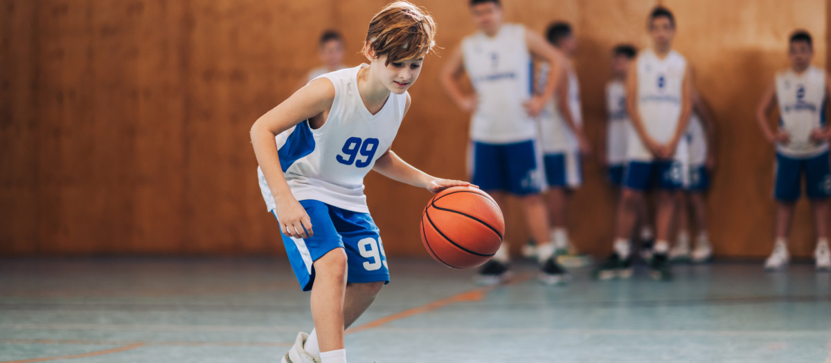 Un adolescente practicando baloncesto junto a sus compañeros de equipo