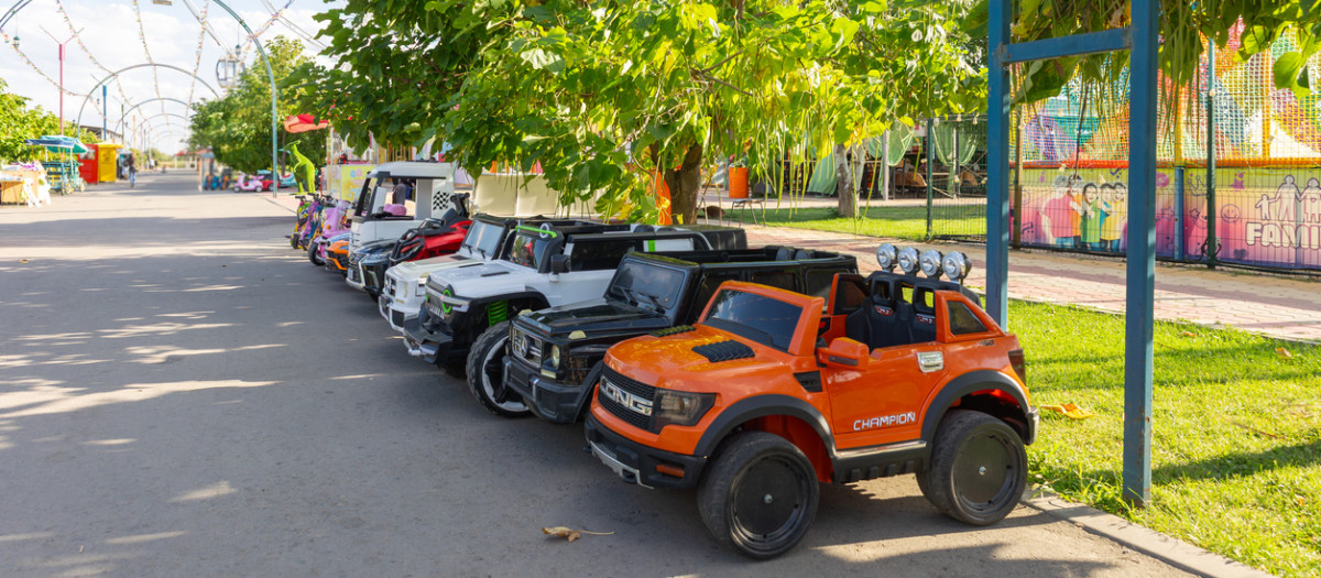 Several colorful electric toy cars are parked in an amusement park, ready for children to enjoy driving them