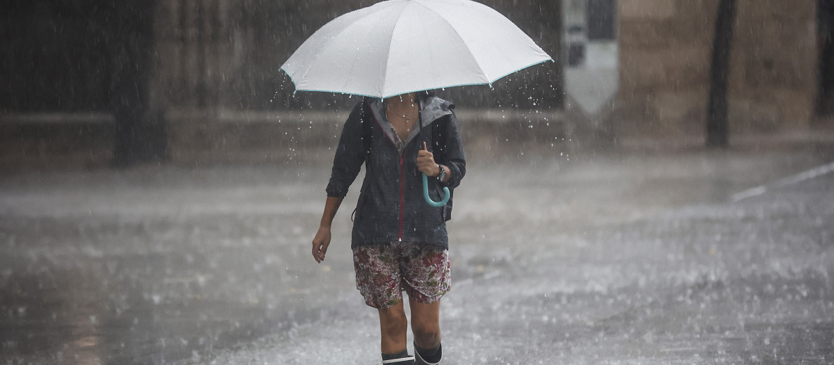 Imagen de una mujer protegiéndose de la lluvia en Valencia