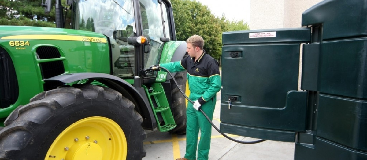 Un agricultor llena el depósito de su tractor con gasóleo agrícola