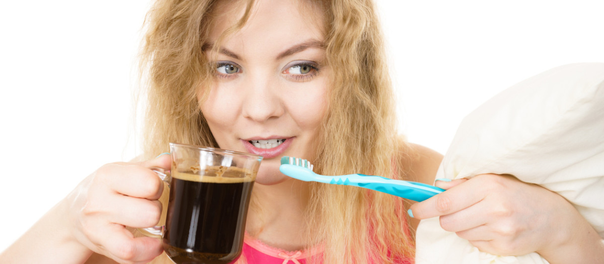 Happy woman holding toothbrush and coffee going to brush her teeth after hot drink.