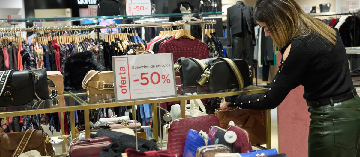 Una mujer observa un bolso, en los primeros minutos de rebajas