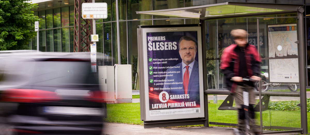 Un ciclista pasa junto a un cartel electoral con la imagen de Ainars Slesers, líder del partido político Letonia Primero