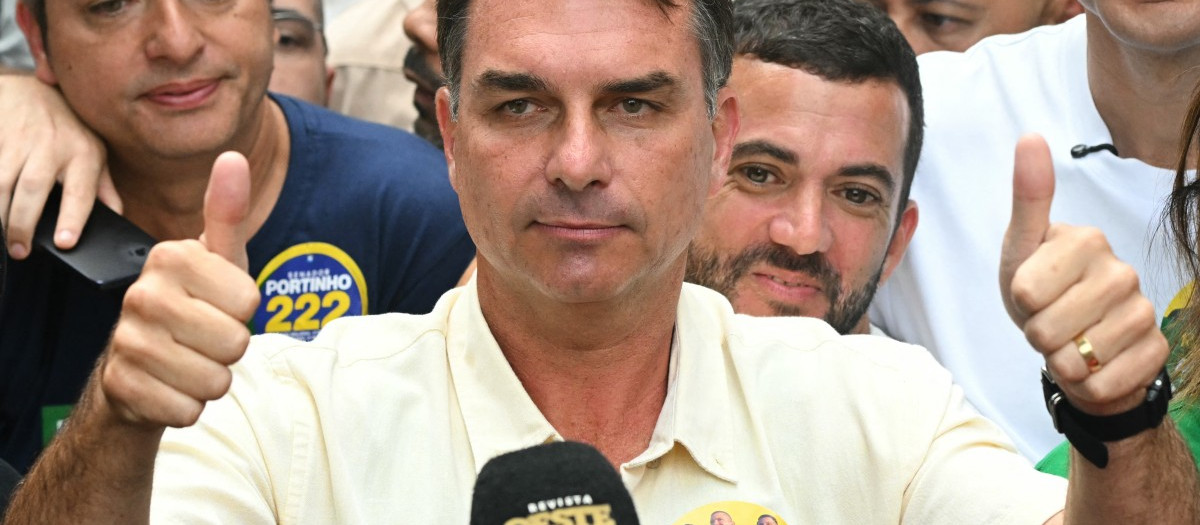 Brazil's right-wing senator and presidential candidate for the Liberal Party (PL) Flavio Bolsonaro gives thumbs up in front of Rio de Janeiro gubernatorial candidate Douglas Ruas (C, back), as he leaves a polling station after voting during the presidential election in Rio de Janeiro, Brazil, on October 4, 2026. Brazilians head to the polls deeply polarized in a nail-biting first-round presidential election and under the shadow of US President Donald Trump, who has backed conservative candidates in recent elections in Latin America. (Photo by MAURO PIMENTEL / AFP)
