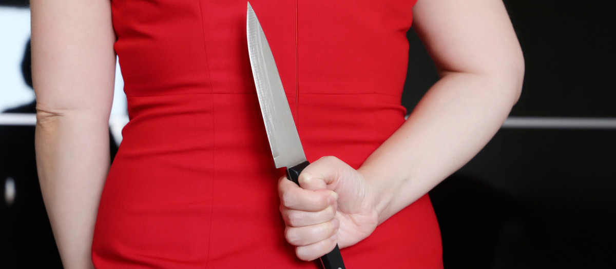 Una mujer esconde un cuchillo en su espalda