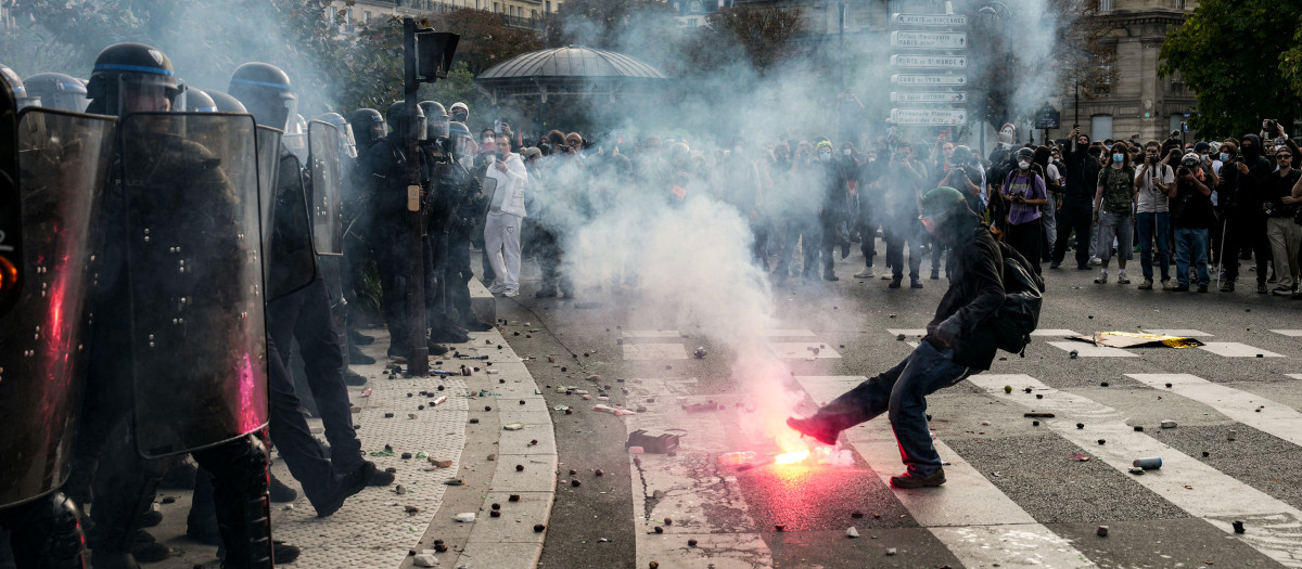 Una persona patea una bengala contra los agentes de policía que dispersan a los manifestantes al final de una protesta que forma parte de una jornada nacional de movilizaciones convocada por estudiantes de secundaria