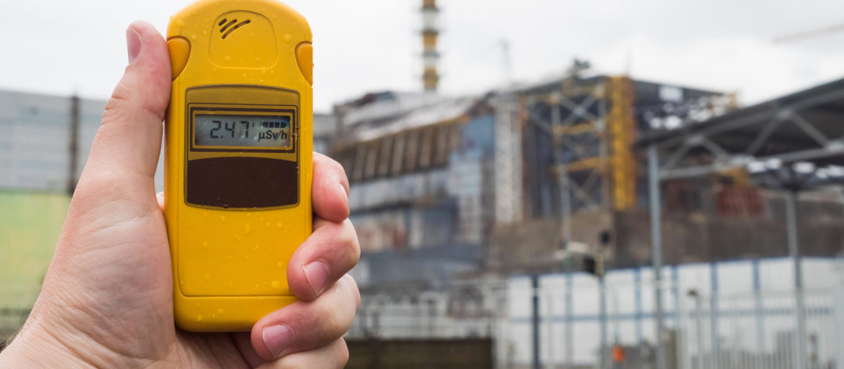 Radiómetro en mano con el cuarto reactor de Chernóbil al fondo