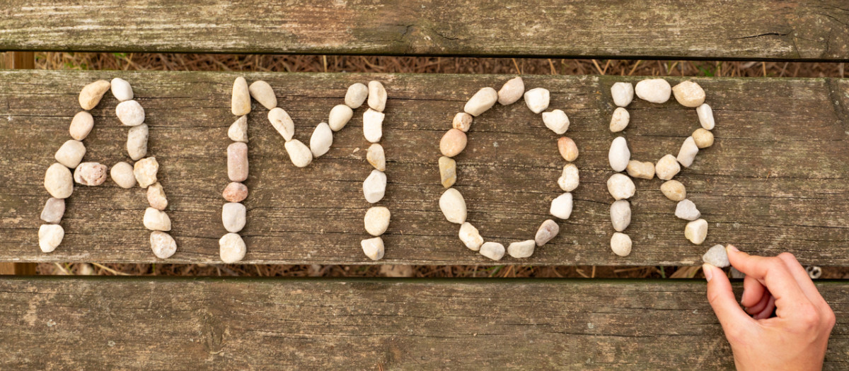 the word amor written with a little bit stones on a wood table and a hand is putting one of them