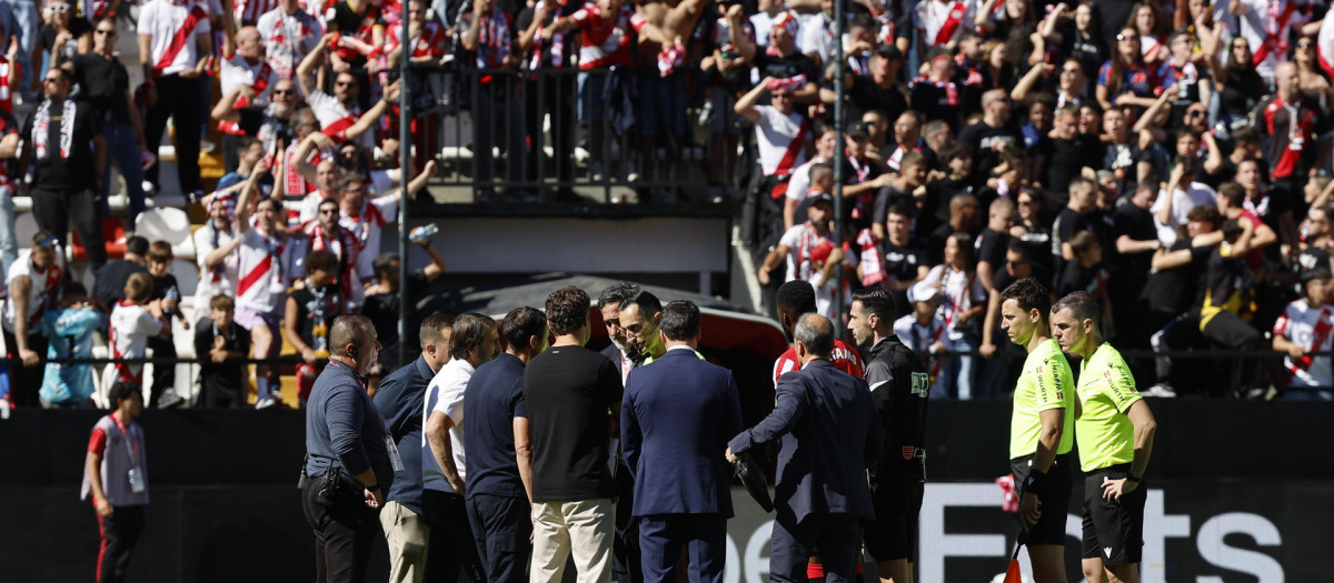 El árbitro José María Sánchez Martínez (c) habla con miembros de ambos equipos antes de comunicar la suspensión definitiva del partido entre el Rayo Vallecano y el Athletic