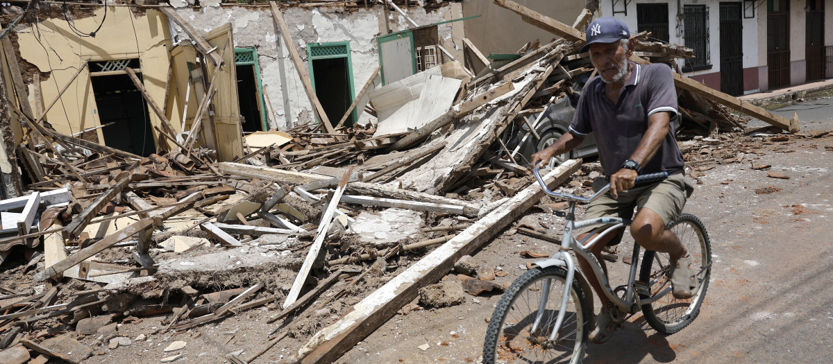 Un hombre pasa en bicicleta frente a escombros de casas dañadas por el terremoto