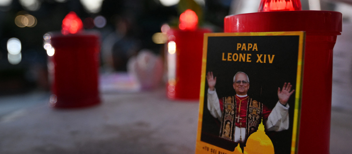 Una fotografía del papa León XIV y unas velas colocadas junto a la estatua de Juan Pablo II frente al Hospital Universitario Gemelli