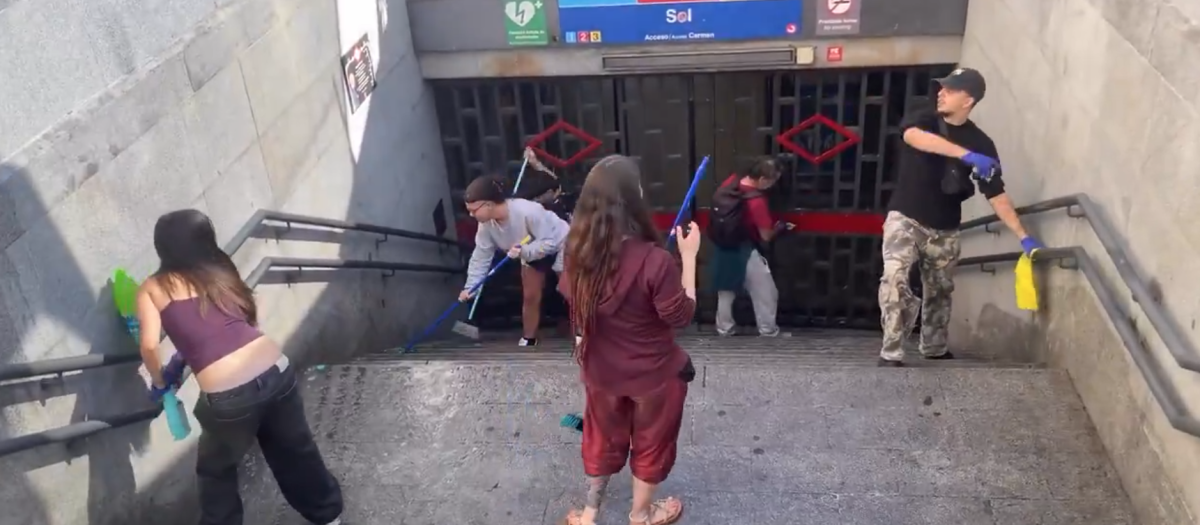 Varias de las personas acampadas limpian los exteriores de la estación de Sol