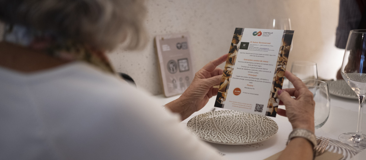 Imagen de archivo de una mujer consultando una de las cartas de Castelló Ruta de Sabor
