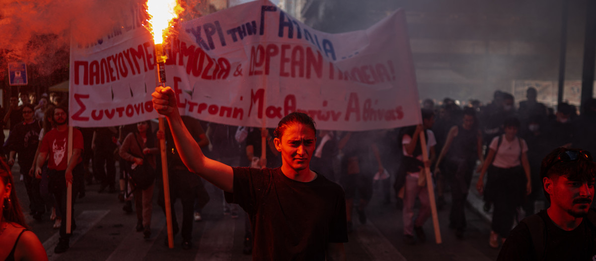 Un manifestante sostiene una bengala mientras estudiantes, profesores y funcionarios participan en una concentración para protestar contra el alto costo de la vida