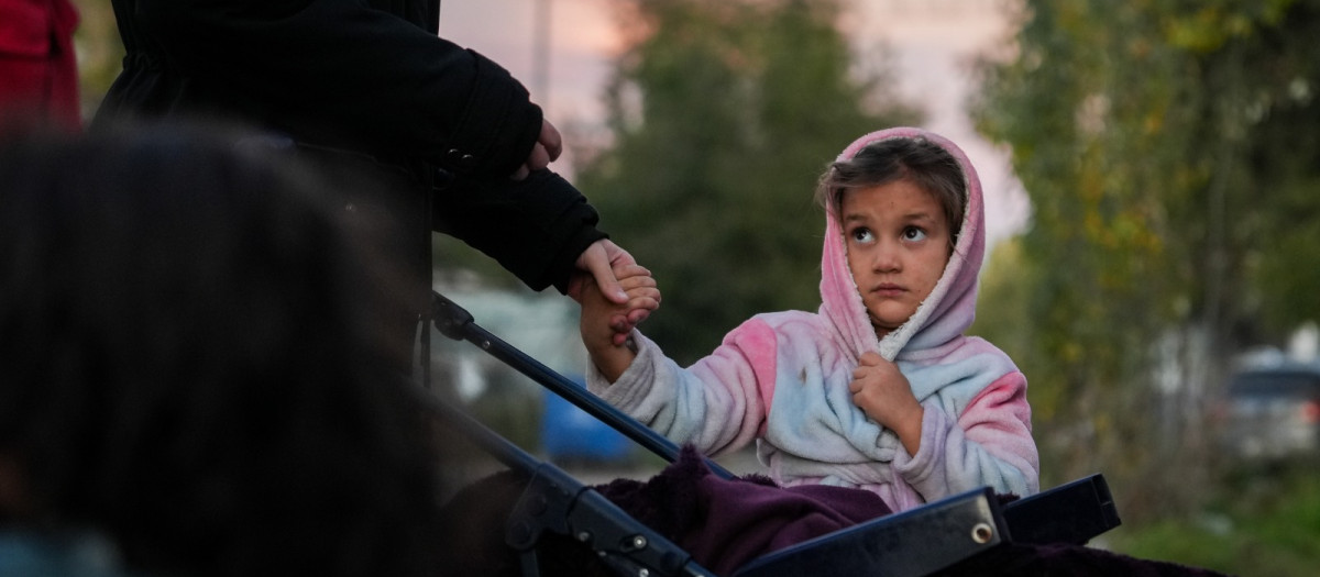 Una niña espera junto a su madre en las "colas del hambre" de la Fundación Madrina