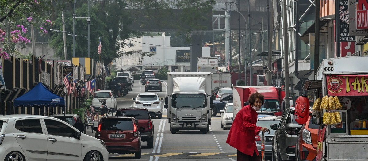 Una mujer lleva una mascarilla mientras camina por una calle de Kuala Lumpur