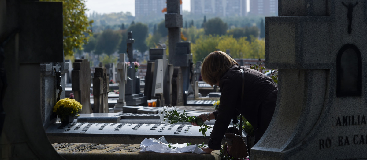Una mujer lleva flores a un ser querido, en el Cementerio de la Almudena