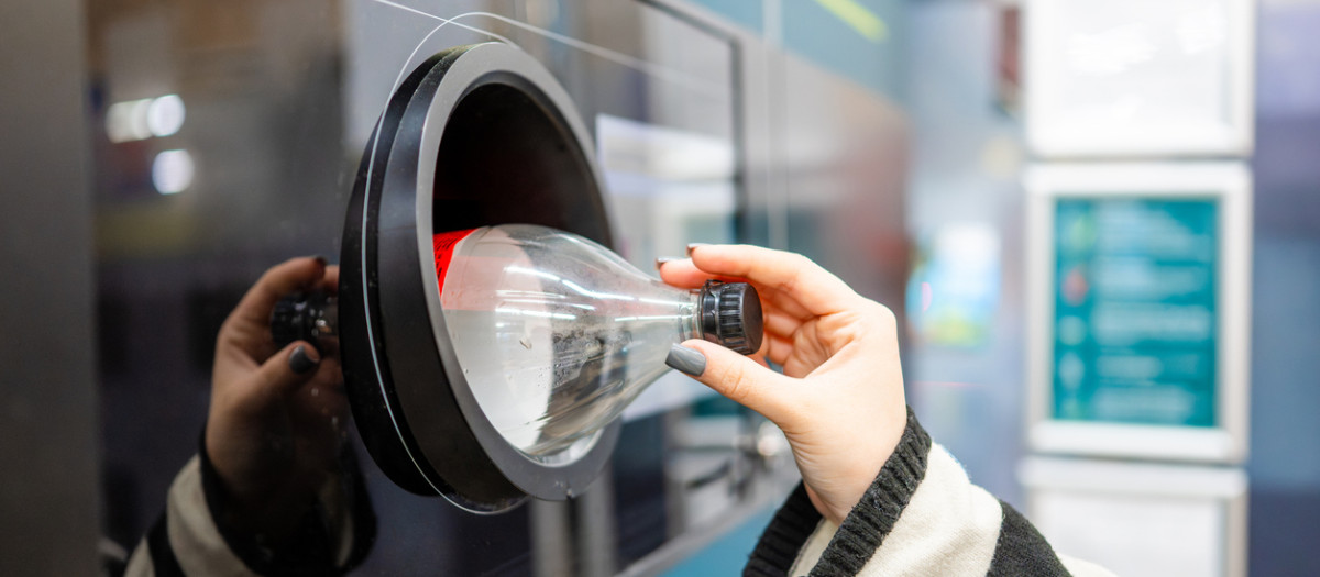 Una mujer devuelve una botella de refresco en una máquina habilitada para ello