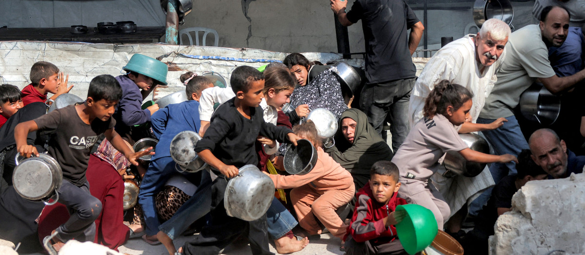 Varias personas buscan refugio ante un presunto ataque con drones mientras hacen fila para recibir comida en un comedor social en el campamento de refugiados palestinos de Jabalia, en el norte de la Franja de Gaza