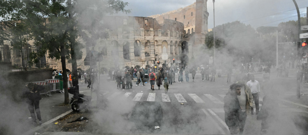 El humo se eleva de un contenedor de basura incendiado por manifestantes frente al Coliseo durante una protesta