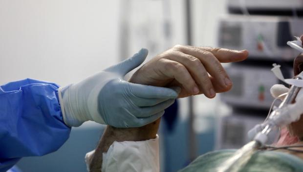 Un médico sostiene la mano de un enfermo