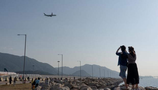 Dos pasajeros le hacen fotos a un avión durante una de las paradas del itinerario