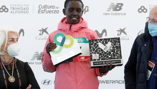 La atleta keniana Nancy Jelagat entre Juan Roig y Hortensia Herrero, recoge el premio tras ganar el maratón de Valencia Trinidad Alfonso DEP con un tiempo de oficioso de 2:19:30