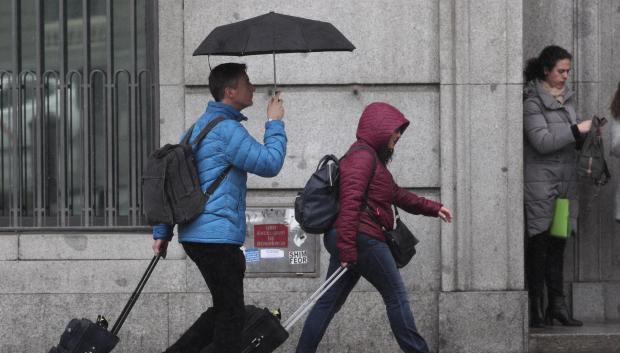 Dos turistas se refugian de la lluvia con paraguas, en Madrid en noviembre.