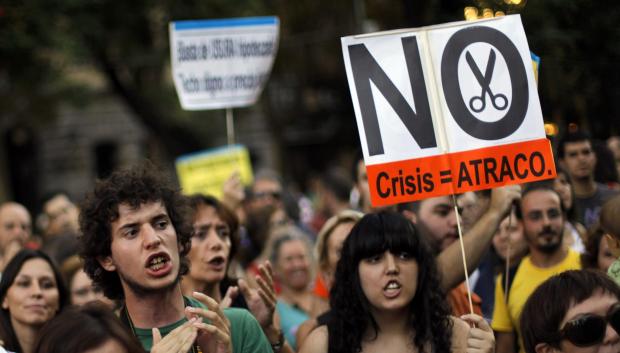 Un manifestante sostiene una pancarta que dice "sin recortes financieros, crisis es igual a atraco" en 2012