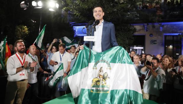 El presidente de la Junta de Andalucía, Juanma Moreno, posa con la bandera de la comunidad en la celebración de su victoria electoral