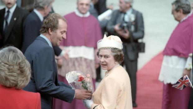 La Reina Isabel II, acompañada del rey Juan Carlos, atiende a las muestras de cariño de los súbditos británicos con banderitas, que les esperaban en la puerta de la Catedral sevillana en 1988