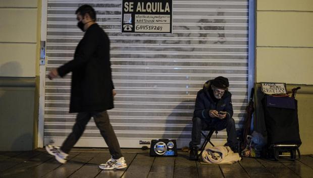Un viandante pasa frente a una persona sin hogar en una calle de Barcelona