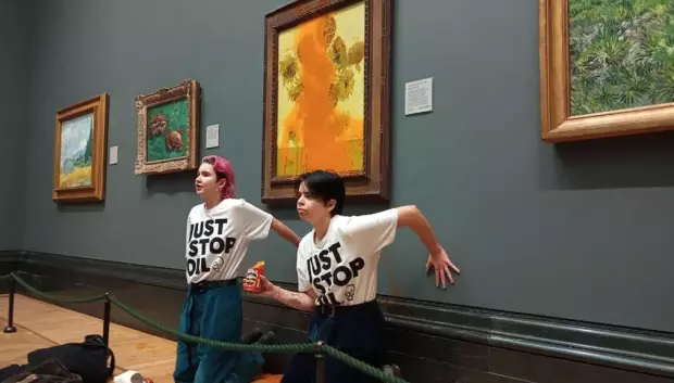Dos activistas permanecen con la mano pegada a la pared de la National Gallery tras arrojar sopa de tomate al célebre cuadro 'Los girasoles', de Vincent van Gogh, el 14 de octubre de 2022