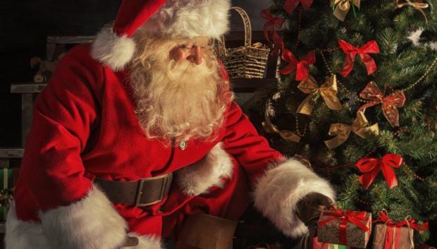 Papá Noel dejando regalos debajo del árbol