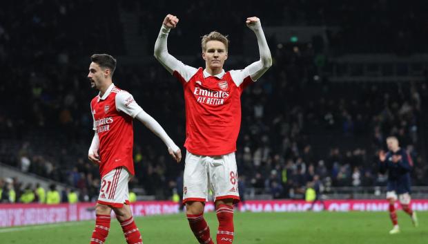 Arsenal's Norwegian midfielder Martin Odegaard (C) celebrates with teammates on the pitch after the English Premier League football match between Tottenham Hotspur and Arsenal at Tottenham Hotspur Stadium in London, on January 15, 2023. - Arsenal won the game 2-0. (Photo by ADRIAN DENNIS / AFP) / RESTRICTED TO EDITORIAL USE. No use with unauthorized audio, video, data, fixture lists, club/league logos or 'live' services. Online in-match use limited to 120 images. An additional 40 images may be used in extra time. No video emulation. Social media in-match use limited to 120 images. An additional 40 images may be used in extra time. No use in betting publications, games or single club/league/player publications. /