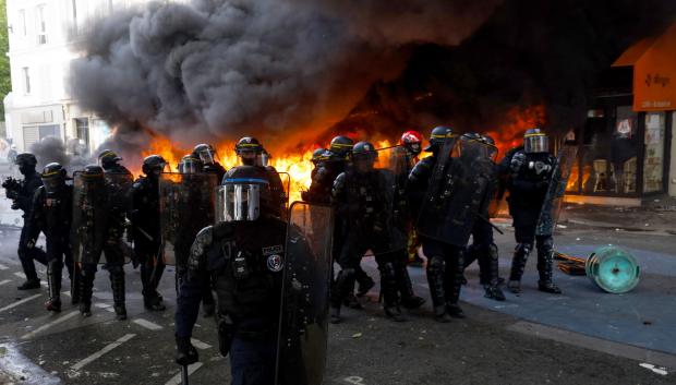 Policías del Cuerpo de Seguridad Republicano Francés y agentes de policía toman posición junto a una estación de bicicletas compartidas en llamas