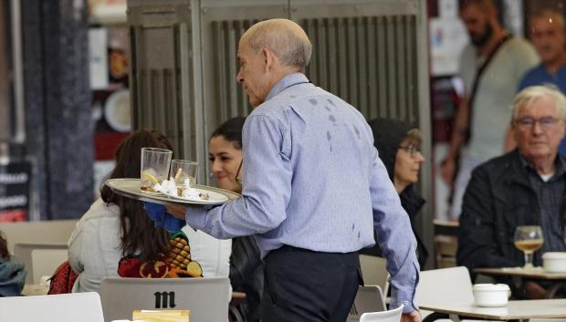 Un camarero porta una bandeja en una terraza de un bar de Madrid.