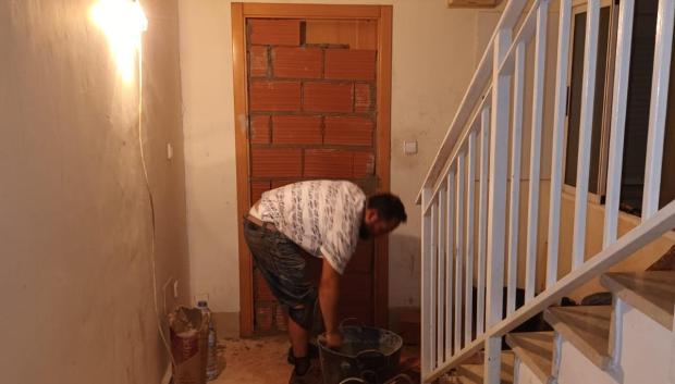 Un albañil tapia la entrada a una de las viviendas