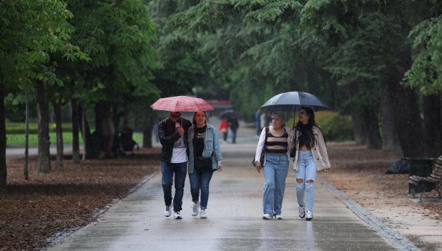 Varias personas se protegen de la lluvia en el Parque del Retiro, en Madrid