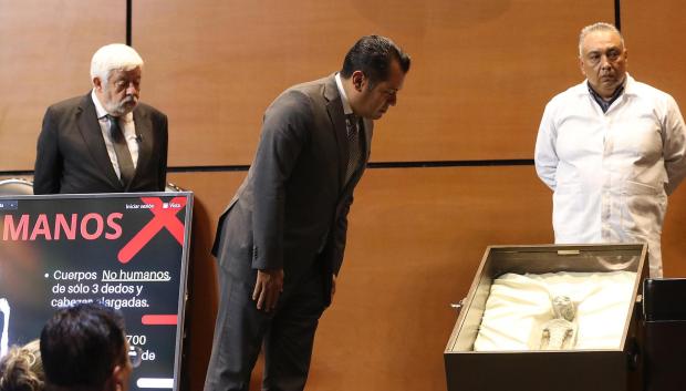 El ufólogo Jaime Maussan (i) y el diputado Sergio Carlos Gutiérrez (c) observan el cuerpo de un presunto extraterrestre en la Cámara de Diputados de México