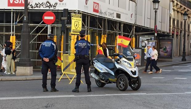 Dos agentes de la Policía Municipal junto a una moto con la bandera de España