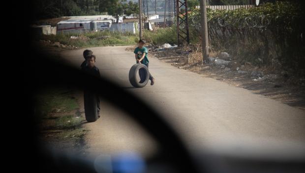 Unos niños de uno de los campos de refugiados juegan con unos neumáticos