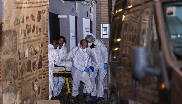 Miembros de los servicios funerarios trasportan uno de los cuatro cadáveres encontrados hoy martes en la calle Santa Leocadia de Toledo
