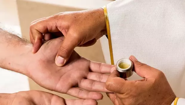Ungir las manos del enfermo, uno de los signos del sacramento