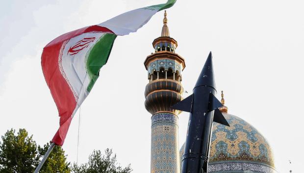 Los iraníes levantan una bandera y la maqueta de un misil durante una celebración tras el ataque con misiles y drones de Irán contra Israel, el 15 de abril de 2024, en la plaza Palestina en el centro de Teherán