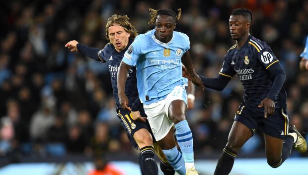 Jeremy Doku (C) de Manchester City en acción contra Luka Modric (L) y Eduardo Camavinga del Real Madrid durante los cuartos de final de la Liga de Campeones